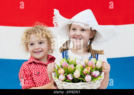 Piccolo olandese ragazzo e una ragazza indossando il tradizionale costume nazionale, abito e cappello cestello di contenimento dei tulipani a bandiera dei Paesi Bassi. I bambini con souve Foto Stock