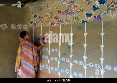 Una donna richiama i motivi tradizionali su una parete della sua casa di villaggio Tikoil in Nachole upazila di Chapainawabganj distretto del Bangladesh. Più di fift Foto Stock