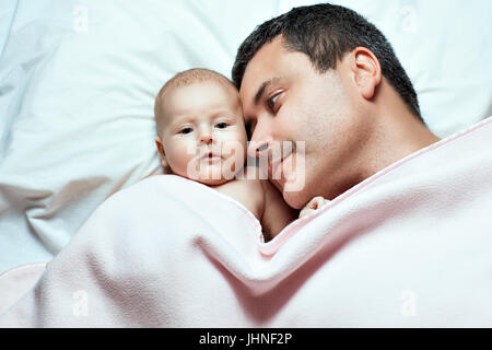 Il padre e la sua bambina giacente al di sotto di una coperta. Padre guarda la figlia Foto Stock