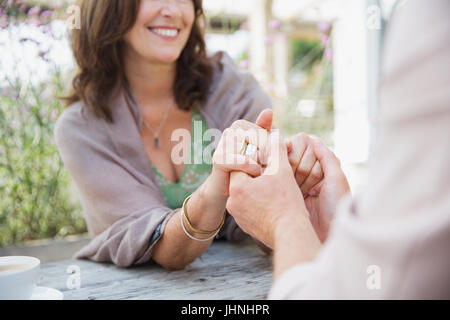 Close up affettuosa coppia matura tenendo le mani sul tavolo del patio Foto Stock