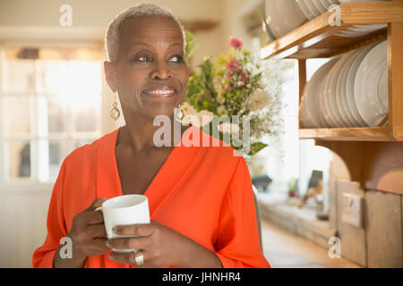 Sorridente donna senior di bere il caffè in cucina Foto Stock