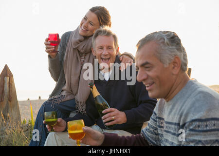 Matura giocosi amici bevendo champagne sulla spiaggia Foto Stock