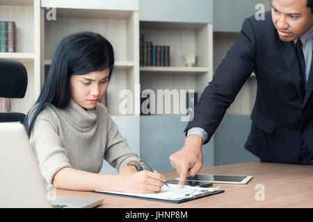 Segretario asiatica sottolinea quando il suo manager è il puntamento e viene imputato per un lavoro difettoso. Segretario e manager in ufficio. Foto Stock