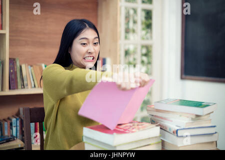 Donna asiatica studentessa universitaria in rage ripping strappo fino il suo libro quando lei la lettura di libri di non capire. Foto Stock