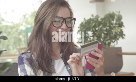 Donna in possesso di una carta di credito e utilizzando il telefono cellulare per gli acquisti online Foto Stock