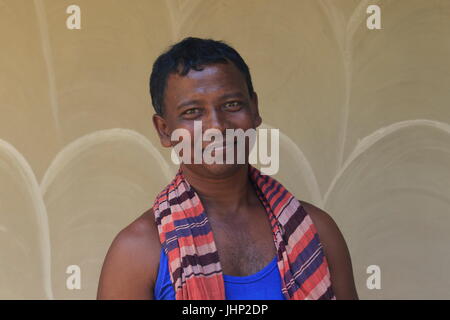 Un uomo di Santal comunità indigena si erge di fronte al loro tradizionale casa di fango Tikoil villaggio in Nachole upazila Chapainawabganj del distretto di B Foto Stock