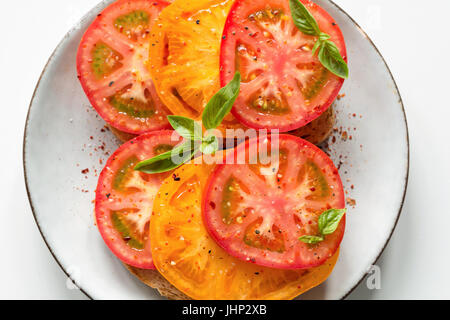 Pomodori e basilico su una piastra Foto Stock