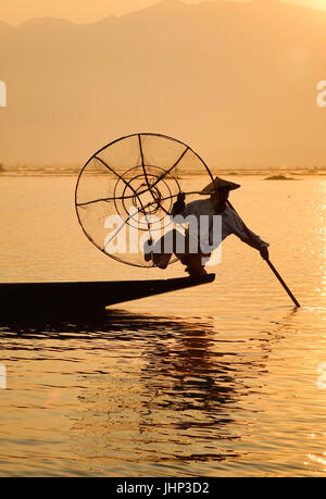 Un pescatore Intha utilizzando i suoi metodi unici di canottaggio e la cattura di pesce sul Lago Inle alla mattina presto nello stato di Shan, Myanmar. Foto Stock