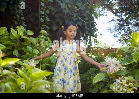 Ragazza in piedi in mezzo a piante verdi in giardino Foto Stock