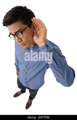 Ritratto di imprenditore coppettazione le orecchie mentre in piedi contro uno sfondo bianco Foto Stock