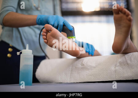Sezione bassa del ragazzo la ricezione di scansione ad ultrasuoni su piedi dal fisioterapista femmina in ospedale Foto Stock
