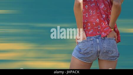 Composito Digitale del retro della donna la parte inferiore del corpo con le mani nelle tasche contro sfocata giallo e sfondo blu Foto Stock