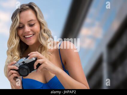 Digital composito della millenaria donna che guarda la telecamera contro edificio sfocato Foto Stock