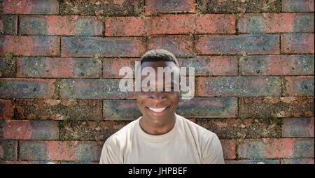 Composito Digitale del soldato felice uomo in piedi contro un muro di mattoni Foto Stock