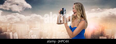 Composito Digitale della donna millenaria con fotocamera contro skyline con le nuvole Foto Stock