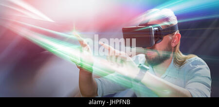 Un uomo indica indossando occhiali per realtà virtuale contro il tavolo moderno nella caffetteria Foto Stock