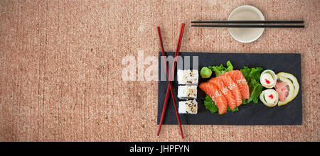 Close up il cibo giapponese con bacchette contro la superficie spiovente Foto Stock