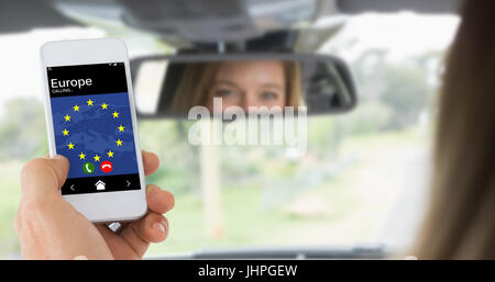 Maschio di mano azienda uno smartphone contro la giovane donna nel sedile del guidatore guardando nello specchio Foto Stock