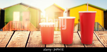 Coppe di rosso su sfondo bianco contro multi capanne colorate sulla sabbia contro il cielo chiaro Foto Stock