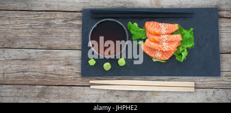 Close up di salmone nella piastra contro il telaio completo di parete in legno Foto Stock