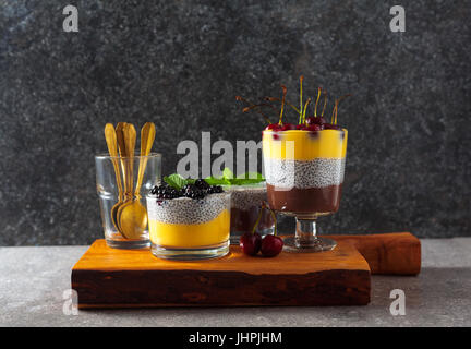 Layered dessert da cioccolato e budino alla vaniglia e anche da chia semi maturi con ciliegie fresche sulla parte superiore e le foglie di menta. Concetto di sano eatin Foto Stock