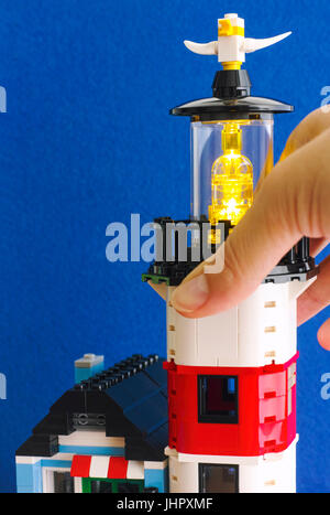 Tambov, Federazione Russa - Giugno 15, 2017 Donna gira a mano su Lego faro luce. Sfondo blu. Studio shot. Foto Stock