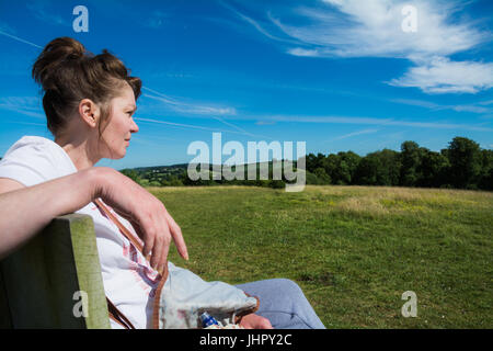 Bella donna di mezza età sat godendo il sole. Estate, UK. Foto Stock