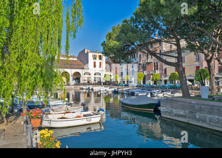 Italia Lago di Garda DESENZANO DEL GARDA porto la mattina presto con barche e ristoranti circostanti in aprile Foto Stock