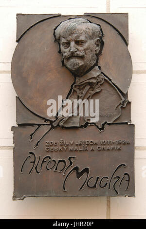 Una lapide commemorativa dedicata al pittore ceco e artista grafico Alfons Mucha sulla casa dove visse nel 1911-1924 a Praga, Repubblica Ceca. La placca progettato da scultore ceca Zdeněk Hošek fu installata nel 1990 in Thunovská Street nel quartiere di Malá Strana). Foto Stock