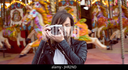 Donna prendendo foto dalla fotocamera digitale nel parco di divertimenti Foto Stock