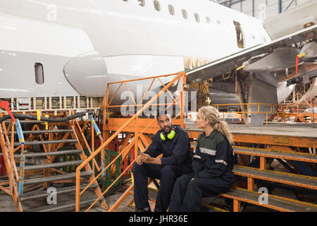 Manutenzione aeromobili ingegneri interagire gli uni con gli altri a compagnie aeree impianto di manutenzione Foto Stock