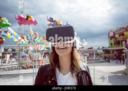 Donna che utilizza la realtà virtuale auricolare nel parco divertimenti Foto Stock
