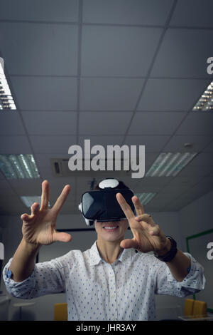 Imprenditrice utilizzando la realtà virtuale auricolare in carica Foto Stock