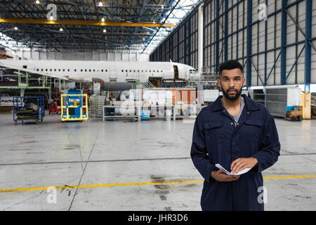 Ritratto di manutenzione aeromobili engineer in piedi presso le compagnie aeree impianto di manutenzione Foto Stock