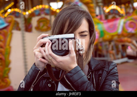 Donna prendendo foto dalla fotocamera digitale nel parco di divertimenti Foto Stock