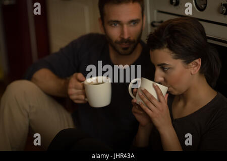 Coppia giovane avente il caffè seduti in cucina a casa Foto Stock