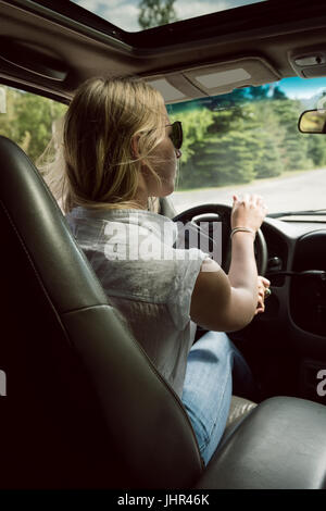 Vista posteriore del giovane donna alla guida di auto sulla strada di campagna Foto Stock