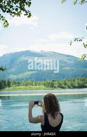 Vista posteriore della donna di scattare le foto con il telefono cellulare Foto Stock