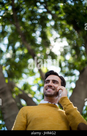 Uomo sorridente parlando al telefono mobile in posizione di parcheggio Foto Stock