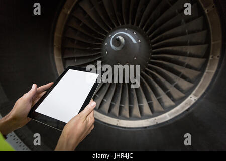 Aeromobili femmina tecnico manutenzione esaminando il motore della turbina di un aereo a compagnie aeree impianto di manutenzione Foto Stock