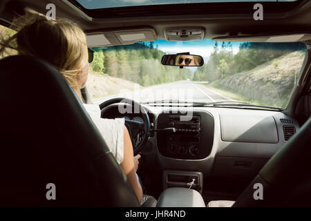 Vista posteriore della donna alla guida di auto sulla strada di campagna Foto Stock