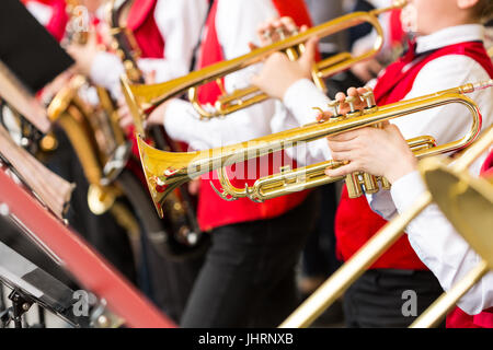 Banda di ottoni, strumenti musicali e orchestra concetto - closeup ensemble di musicisti di suonare su trombe per le note in rosso concerto costumi, mano maschio Foto Stock