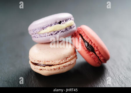 Tre mescolati macarons sulla scheda di ardesia Foto Stock