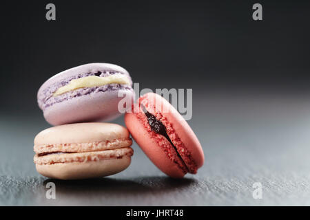 Tre mescolati macarons sulla scheda di ardesia Foto Stock