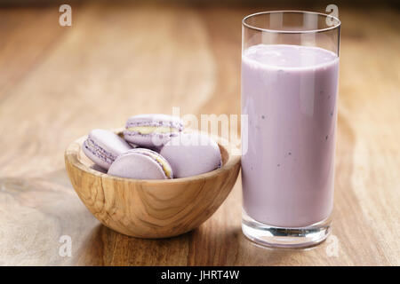 Violetta macarons nella ciotola di legno con mirtillo yogurt sul tavolo di legno Foto Stock