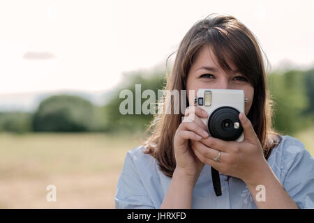 Bella giovane con i capelli lunghi ragazza con fotocamera istantanea. Foto Stock