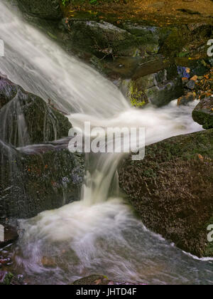 In prossimità di una sezione di una cascata che scorre a destra, a sinistra e a destra tra le rocce umide Foto Stock