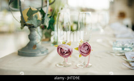 Due bicchieri per gli sposi sposa decorate con bellissime rose stand sul tavolo durante la celebrazione dei matrimoni. Close up Foto Stock