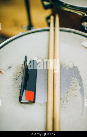 Primo piano di cosce di pollo disossate e carta di rotolamento giacenti sul drum set. Il batterista attrezzature Foto Stock