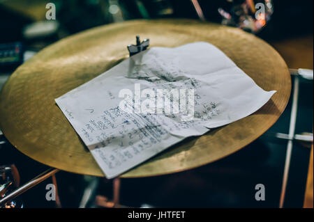 Primo piano delle liriche di carta con un testo della canzone giacente sul drum set. Musicista dettaglio di apparecchiature Foto Stock
